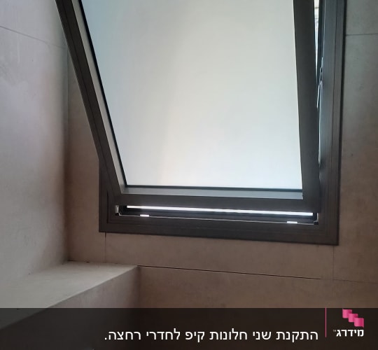 חלון ציר מאלומיניום כהה עם זכוכית חלבית בחדר רחצה